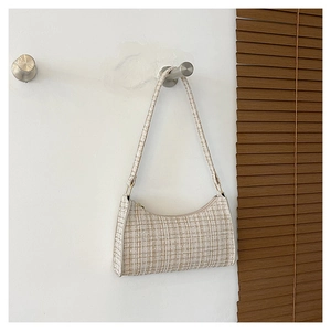 Détail de la texture tissée crème et de la bandoulière en tissu d'un sac sous l'aisselle