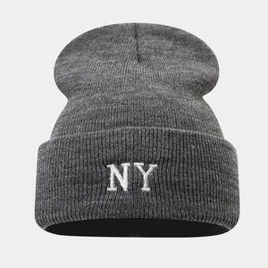 Close-up of white NY embroidery on a dark grey knit beanie with ribbed texture