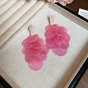 Detailed close-up of pink layered shell-style tassel earrings in a cream jewelry box