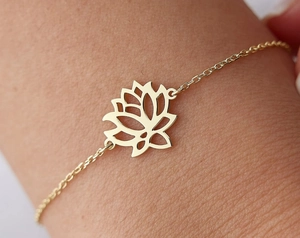 Detailed close-up of a delicate gold lotus pendant bracelet worn on a woman's wrist