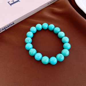 Macro shot of turquoise beaded bracelet with natural veining on dark silk fabric