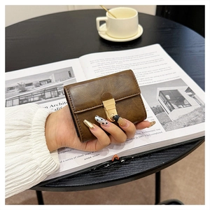 Brown retro leather card holder with a gold metal buckle on a coffee table setting