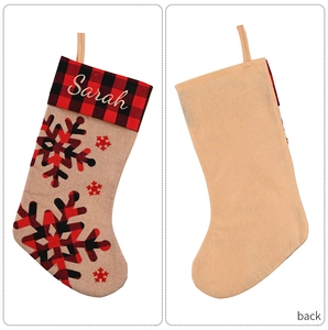 Detail of burlap Christmas stocking with red plaid cuff and snowflake patterns.