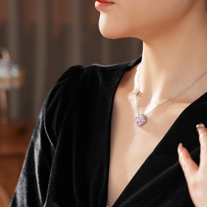 Detail of pink clover zircon pendant necklace on female collarbone with silver chain