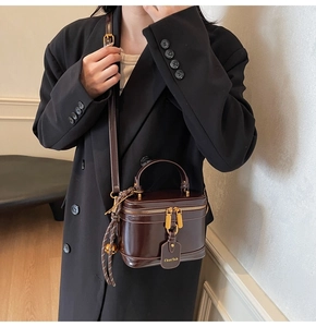 Dark brown patent leather bucket bag with gold zipper shown on model for size perspective