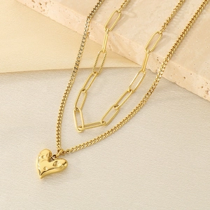 Détail du collier double couche doré avec pendentif cœur martelé et chaîne à trombones