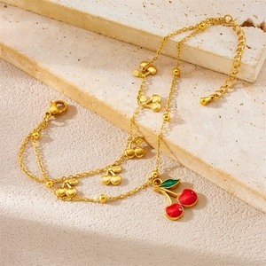 Golden double-layer cherry anklet with red enamel pendant on a natural stone base