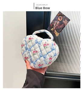 Close-up of quilted floral heart handbag with blue bow patterns and pink rose details
