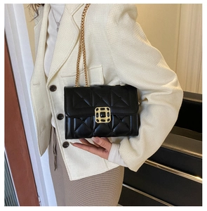 Detail of black quilted leather shoulder bag with gold square buckle and chain strap