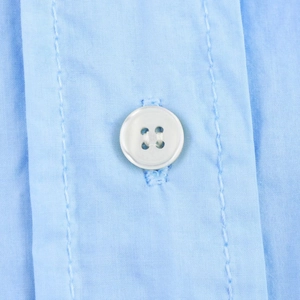 Nahaufnahme eines weißen Harzknopfes und feiner Stoffstruktur auf blauem Hemdkleid