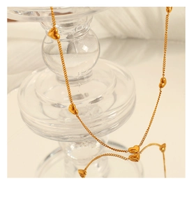 Detailed macro view of heart charm necklace with gold plated chain on glass base