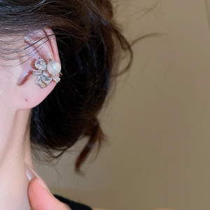 Close-up of silver ear cuff with flower zirconia and white pearl on model's ear