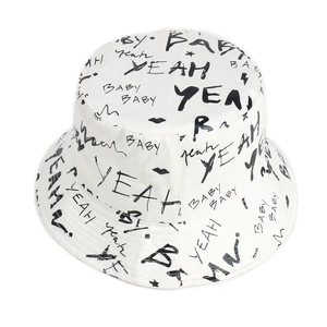 Detailed close-up of white bucket hat with black hand-drawn graffiti style lettering