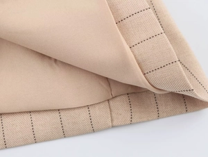 Détail macro du tissu beige à fines rayures avec couture soignée et doublure lisse