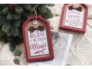 Close-up of a rustic wooden Christmas sign with 'Believe in the Magic' text on white knit