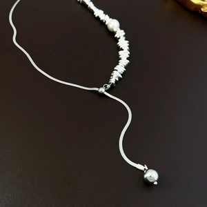 Detail of silver snake chain with irregular metal beads and a white pearl pendant