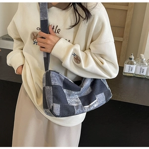 Détail du sac bandoulière en patchwork de denim bleu avec large sangle et surpiqûres