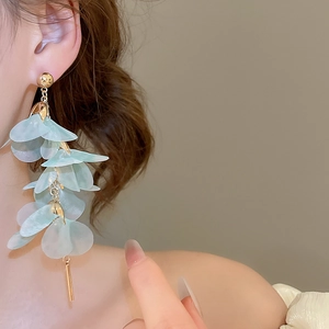 Gros plan de boucles d'oreilles pendantes pétales vert clair avec perles dorées