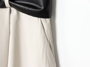 Detailed close-up showing stitching of black leather and beige fabric on fashionable dress