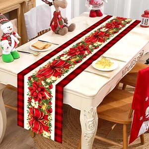 Close-up of Christmas table runner with red poinsettia and buffalo plaid on wooden table