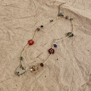 Detail of beaded necklace with cat silhouette pendant and heart bead on vintage paper