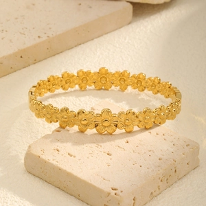Detail of golden stainless steel hollow heart flower bracelet on stone pedestal