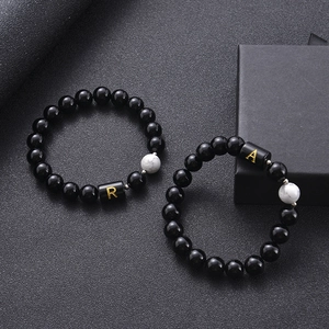 Black agate and white turquoise beaded bracelets featuring gold letter R and A accents