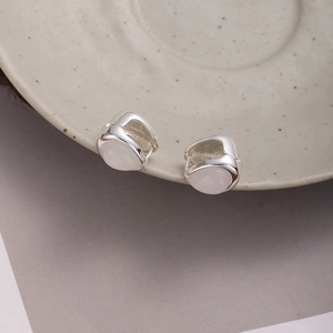 Minimalist silver cat-eye stone teardrop earrings on elegant ceramic display