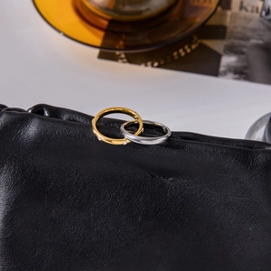 Detail of interlocking gold and silver stainless steel rings with zircon on black leather