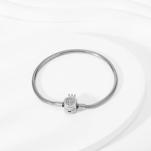 Detailed close-up of a silver snake chain bracelet with a sparkling crown-shaped clasp