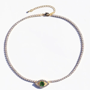 Detail of gold tennis chain necklace with green zircon evil eye pendant in macro view