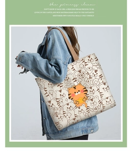 Close-up of a cream canvas tote bag featuring cute cartoon tiger prints and lucky symbols