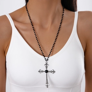 Gothic style long beaded necklace with large hollowed-out cross pendant on a model