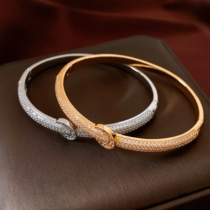 Detailed close-up of gold and silver buckle bracelets with micro-pave crystals on a jewelry box