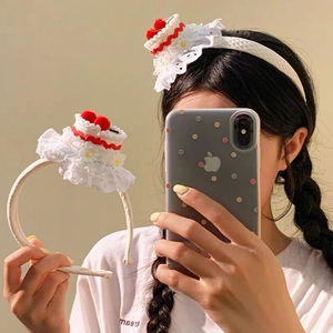 Detailed view of a cute cherry cake headband with white lace trim and floral accents
