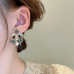 Detail of vintage gold earrings with purple gemstone and pearls worn by a model
