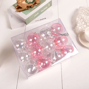 Close-up of pink and iridescent Christmas baubles in a clear gift box on a white wooden desk