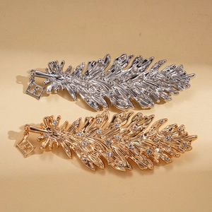 Metallic feather brooches with rhinestones in gold and silver on beige leather