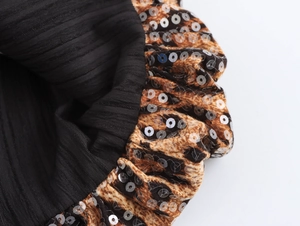 Detail aus schwarzem Rippstoff mit Leopardenmuster und silbernen Pailletten am Kleid