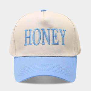 Vue détaillée d'une casquette beige et bleu clair avec broderie HONEY bleue