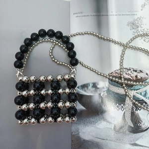 Detail of hand-woven mini beaded bag with black and silver metallic geometric texture