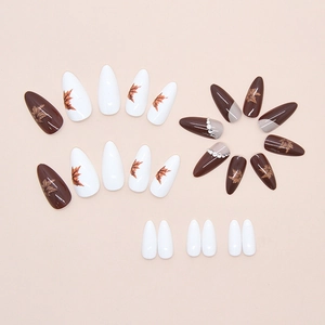 Détail de faux ongles en amande avec motifs feuilles d'érable et strass brillants