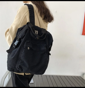 Close-up of black washed canvas backpack showing durable straps and metal zipper detail