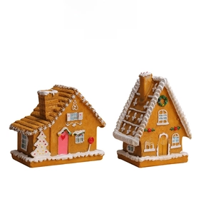 Detail view of two resin gingerbread houses with LED lights and festive Christmas decorations