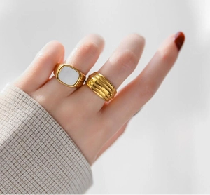 Primer plano de anillo dorado minimalista con incrustación de concha y banda de rosca