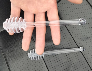Gros plan d'une cuillère à miel transparente avec tête spirale sur cuir noir