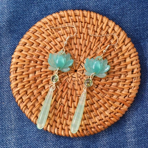 Detailed macro view of Calla Lily enamel drop earrings on a rustic rattan mat