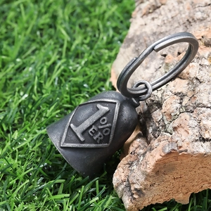 Macro shot of vintage 1%ER guardian bell pendant with aged steel finish on tree bark