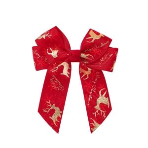 Detail of red grosgrain ribbon bow featuring gold reindeer print and Merry Christmas text