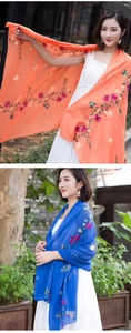 Detail of floral embroidery on lightweight orange and blue silk shawls in sunlight